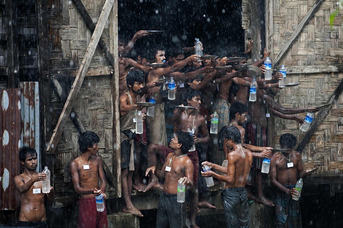 Di dân Bangladesh và Rohingya - được tìm thấy trôi dạt trên biển - hứng nước mưa tại nơi trú ẩn tạm thời ở Rakhine, miền bắc Myanmar - Ảnh: AFP