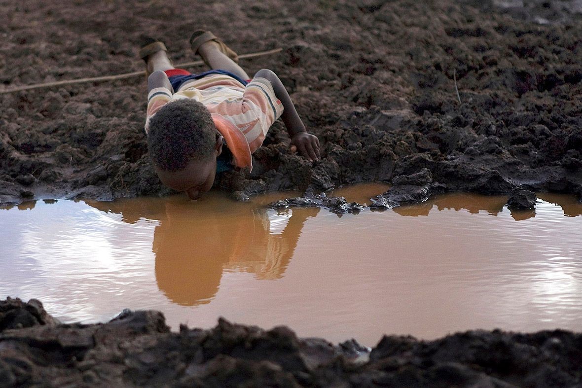 Cậu bé uống nước trong ao làng Bule Duba (Ethiopia) - Ảnh: Reuters